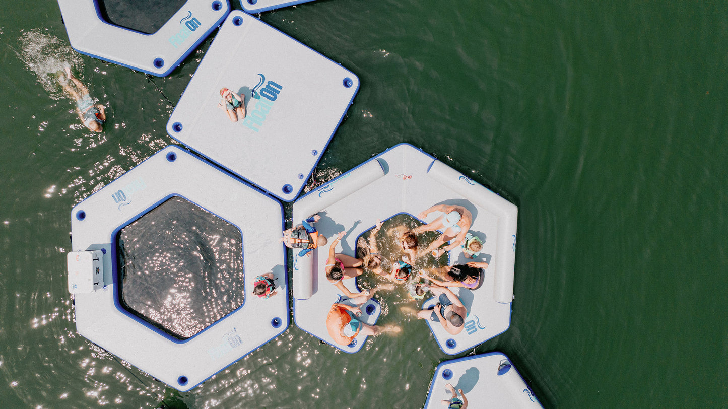 A family relaxing on the water with different inflatable docks and water mats on the lake water.