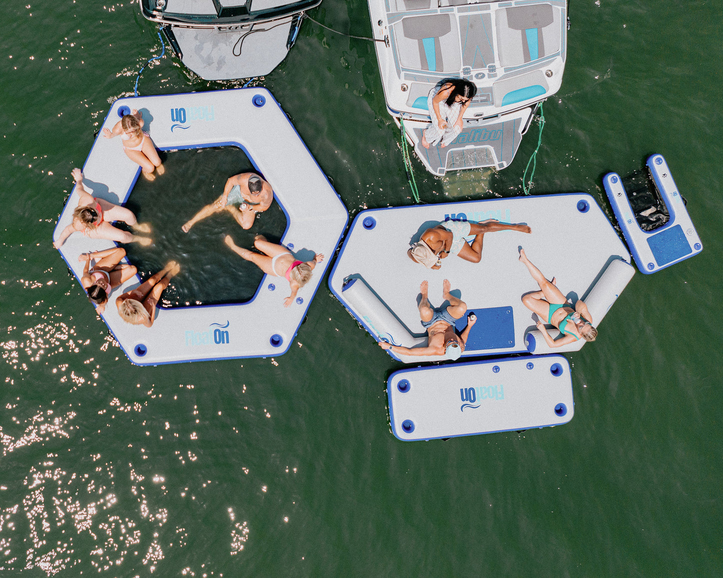 People sitting on the grand oasis inflatable water mat on the lake.
