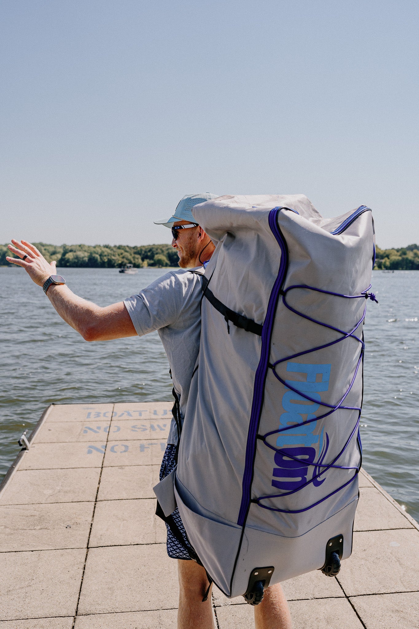 A man carrying a pack that holds the Grand Oasis Inflatable Water Mat from Float On Boat Gear.