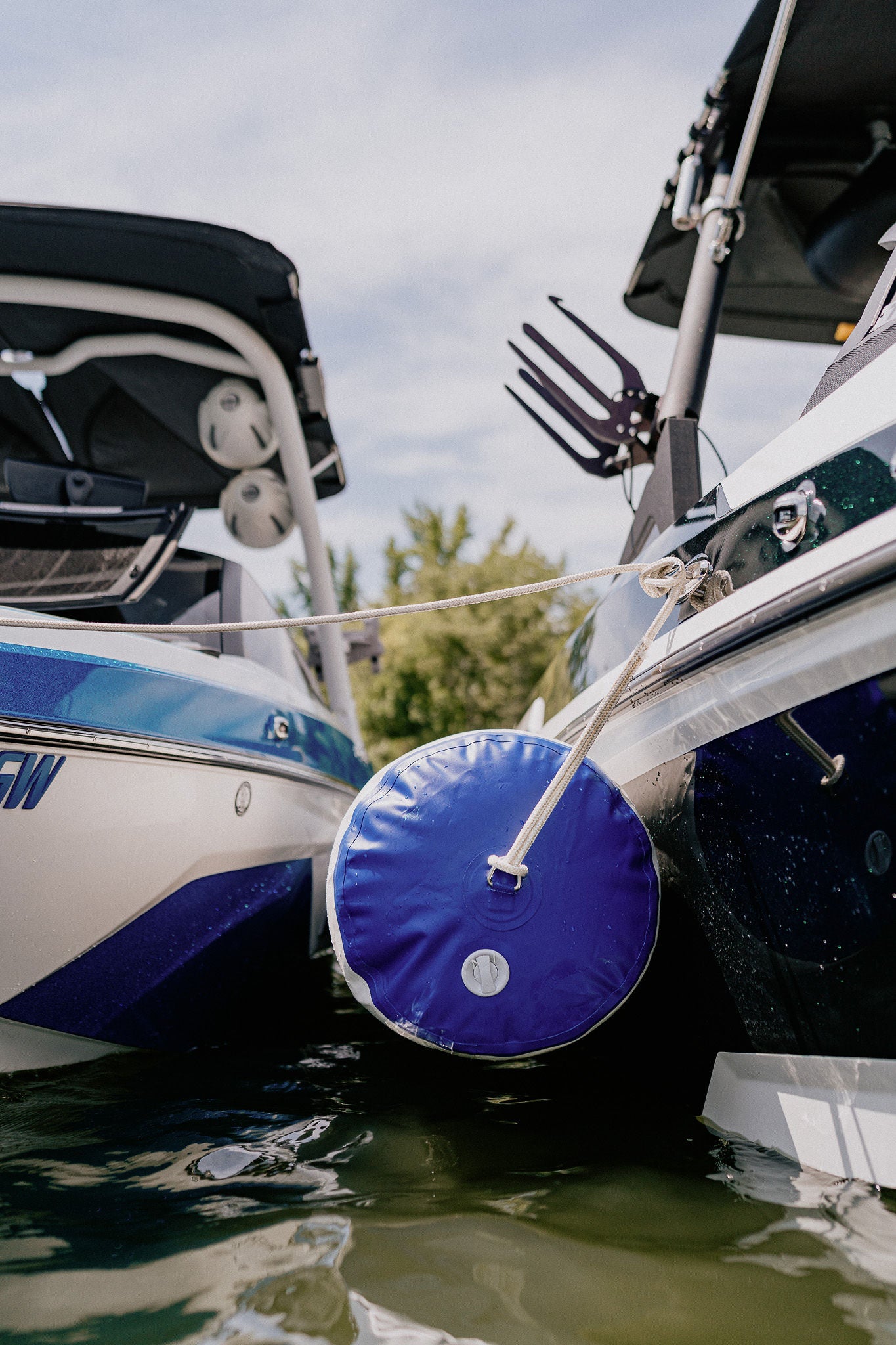 A low view of an inflatable boat fender separating two boats on a lake.